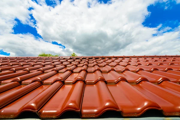 Novo telhado vermelho contra o céu azul nublado — Fotografia de Stock