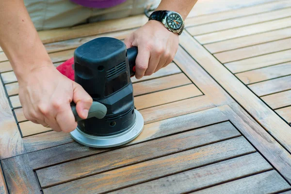 Närbild av snickarens händer arbetar med elektrisk slipmaskin — Stockfoto