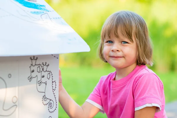 Menina pintando casa de papelão — Fotografia de Stock