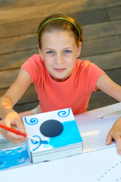 Menina pintando casa de papelão — Fotografia de Stock