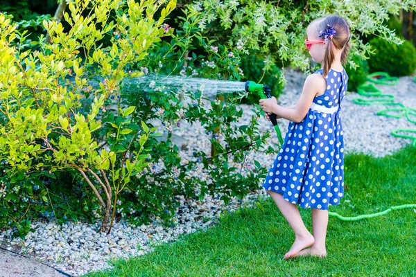 Маленькая счастливая девочка поливает сад — стоковое фото