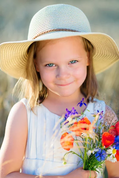 野生の花赤いケシと麦藁帽子で陽気な少女 — ストック写真