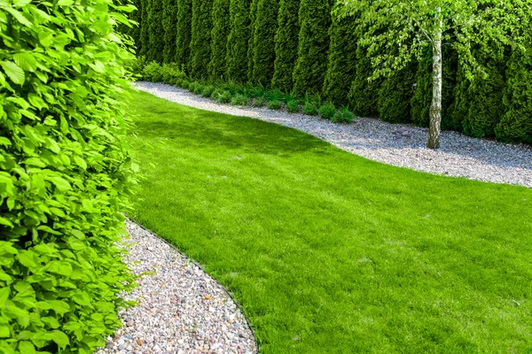 Giardino formale ben curato con un percorso di piccole pietre, siepi e prato verde — Foto Stock