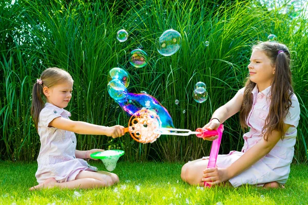 Dzieci bawiące się z różdżki bańka mydlana w parku — Zdjęcie stockowe