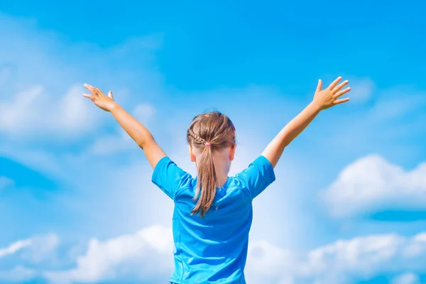 Happy child girl with open arms outdoor under blue sky. — Stock Photo, Image