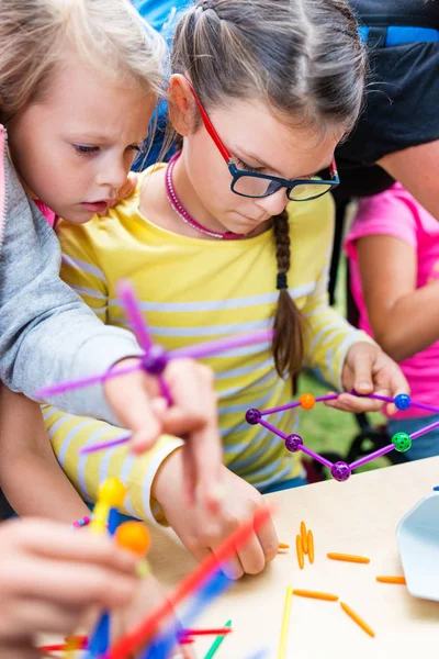 Dvě malé dívky hrát se spoustou barevné plastové tyčinky — Stock fotografie