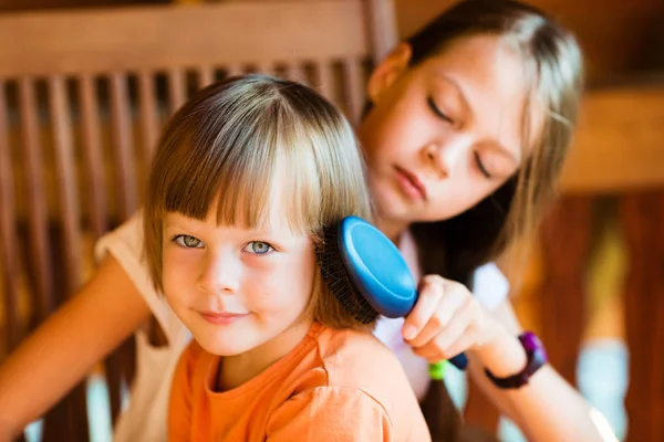 Красива дівчина розчісує волосся молодшої сестри — стокове фото