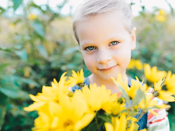 牧草地で黄色の花々 のブーケを持つ少女 — ストック写真