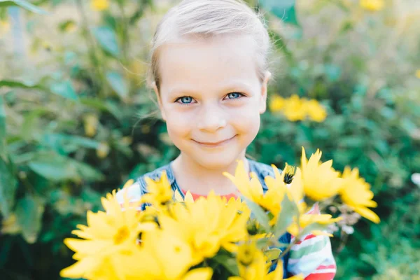 Little girl with a bouquet of yellow wildflowers in a meadow — Stock Photo, Image