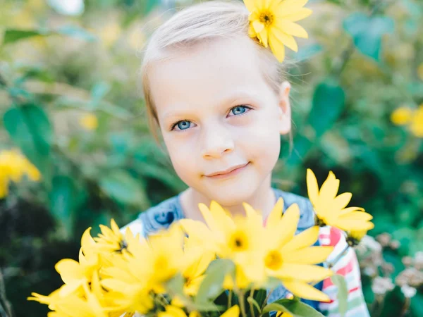 牧草地で黄色の花々 のブーケを持つ少女 — ストック写真