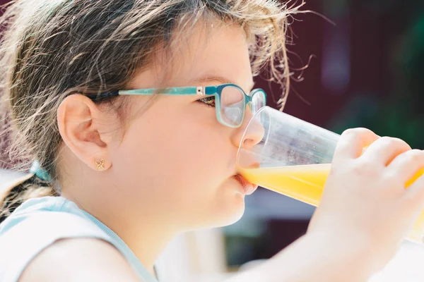 Retrato de uma menina bonita segurando vidro com laranja saborosa — Fotografia de Stock