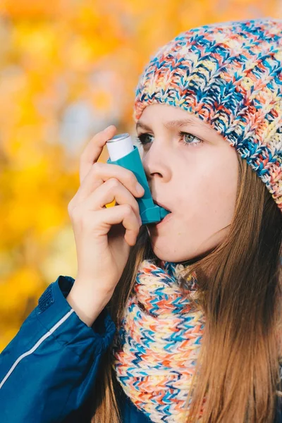 Молодая девушка использует ингалятор от астмы в парке — стоковое фото