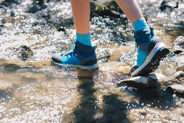 Hiking shoes - sole of trekking boots and legs in a stream