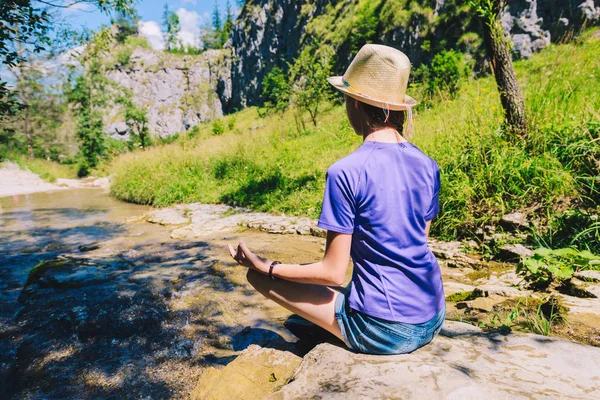 Jovem mulher meditando em ioga posar em um riacho de montanha — Fotografia de Stock