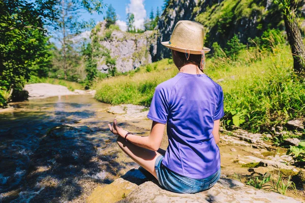 Jovem mulher meditando em ioga posar em um riacho de montanha — Fotografia de Stock