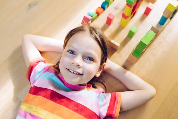 Amused little girl lying on her back on the floor — Stock Photo, Image