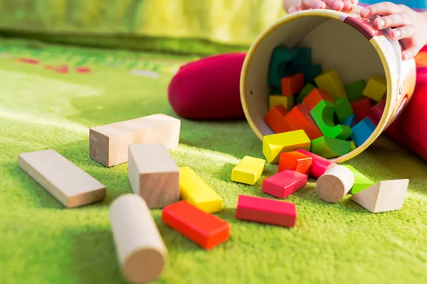 Маленька дитина грає з дерев'яними блоками на зеленому килимі — стокове фото