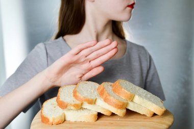Gluten intolerance concept. Young girl refuses to eat white bread clipart