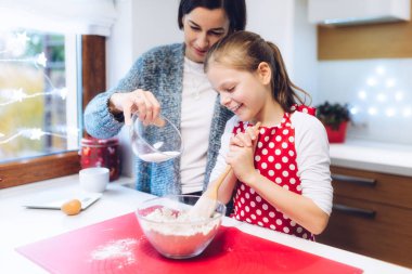 Noel pastanesi. Anne ve kızı zencefilli ekmek yapıyor, yumurta, un, zencefilli ekmek hamuru için bal hazırlıyorlar. Kutlama yemekleri, yemek pişirme süreci, aile yemekleri, Noel ve Yeni Yıl gelenekleri konsepti
