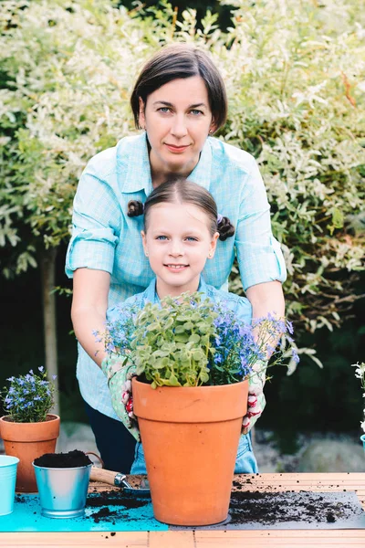 Madre e hija plantando flores en macetas en el jardín — Foto de Stock
