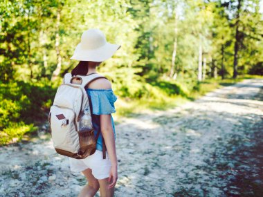 Sırt çantalı genç bir gezgin dağlarda bir dağ yolunda yürüyüş yaparken - gerçek bir kaşif - şapkaya odaklan - sığ bir alan derinliği. Seyahat Konsepti