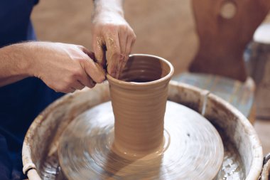 Potter çömlekçi çarkında kil vazo yapıyor.