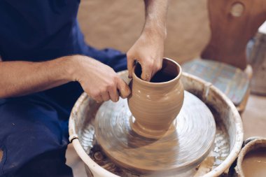 Potter çömlekçi çarkında kil vazo yapıyor.