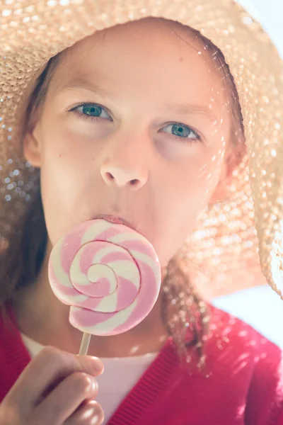 Hasır Şapkalı Küçük Kız Pembe Beyaz Bir Lolipop Yalıyor — Stok fotoğraf