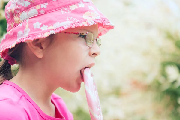 小さな女の子でAピンクの帽子なめる大ロリポップ — ストック写真