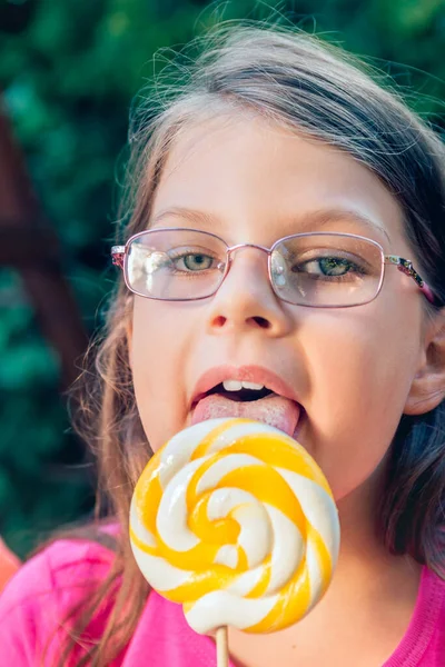 Gözlüklü Küçük Kız Büyük Lolipop Yalıyor — Stok fotoğraf