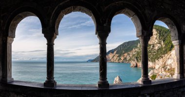 Akdeniz kıyısındaki Portovenere 'deki St. Peter Kilisesi' nin penceresinden Cinque Terre yakınlarındaki Ligurian sahili kemerli taş bir pencereden görülüyor.