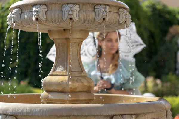 Mädchen am Brunnen mit weißem Regenschirm — Stockfoto