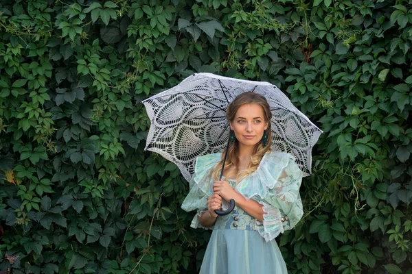 Дівчина на фоні зелених рослин з білою парасолькою — стокове фото