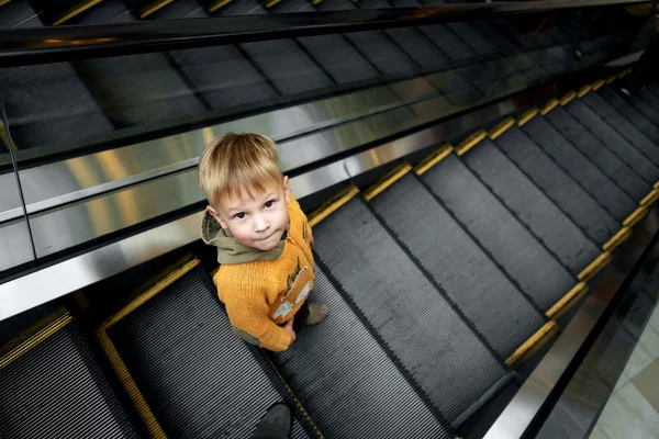 Niño cabalga en una escalera mecánica en una gran tienda — Foto de Stock