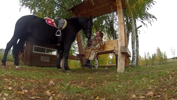 Kız Güz siyah bir at ile bir salıncak üzerinde — Stok video