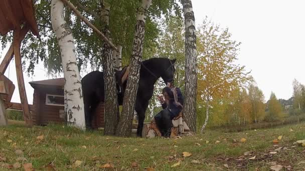 Flicka på en gunga med en svart häst i höst — Stockvideo