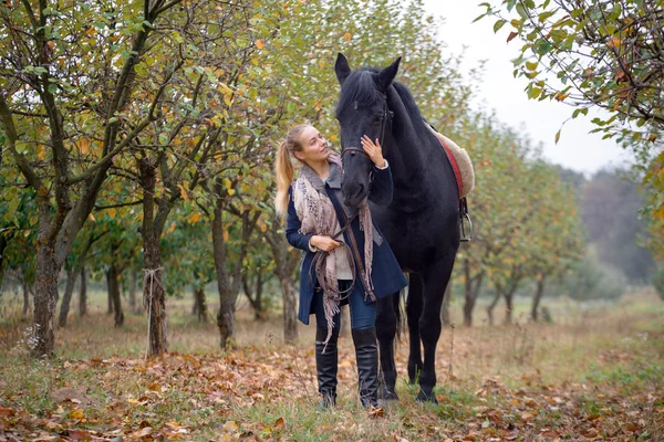 Beautiful stylish girl in a cowboy hat with a horse walking in the autumn forest, country style — Stock Photo, Image
