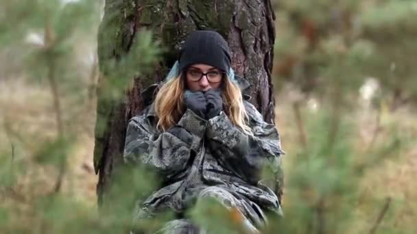 Menina senta-se em um pinheiro em um terno protetor outono — Vídeo de Stock