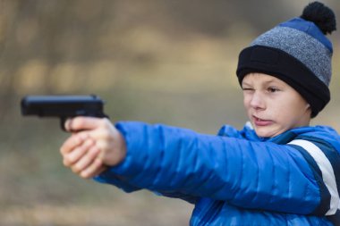 sokakta bir oyuncak tabanca ile sonbaharda oynayan çocuk