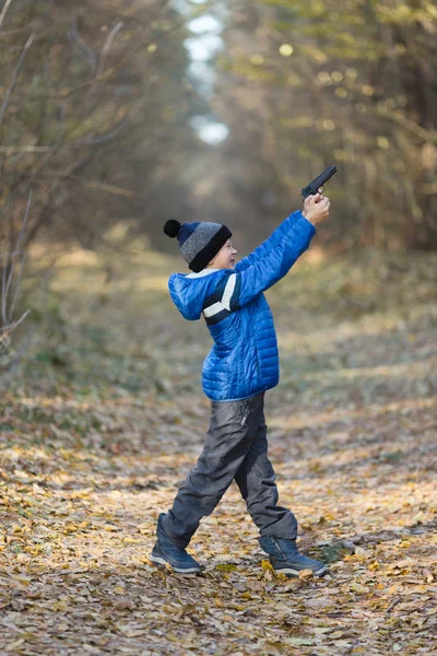 Garçon jouer avec un jouet pistolet dans la rue en automne — Photo