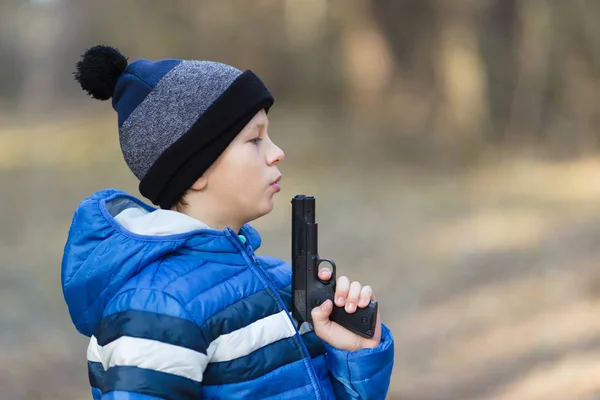 Menino brincando com uma arma de brinquedo na rua no outono — Fotografia de Stock