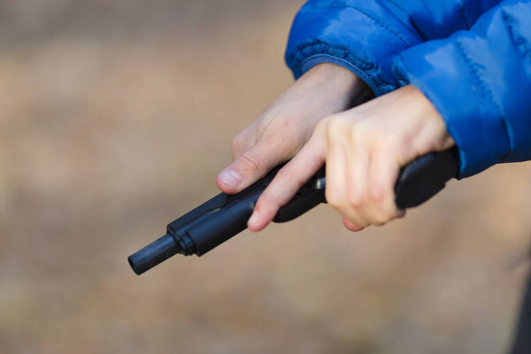 boy playing with a toy gun on the street in autumn