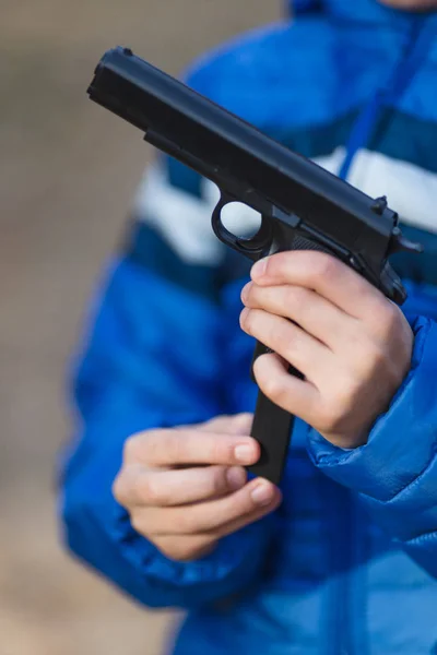 Menino brincando com uma arma de brinquedo na rua no outono — Fotografia de Stock