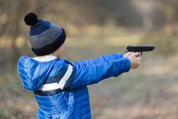 Pojke som leker med en leksakspistol på gatan i höst — Stockfoto