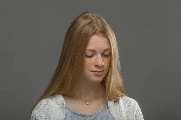 Roodharige meisje close-up op een grijze achtergrond — Stockfoto