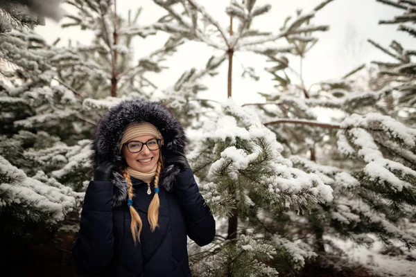 Meisje in een dennenbos in de sneeuw — Stockfoto
