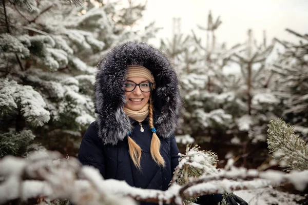 Meisje in een dennenbos in de sneeuw — Stockfoto