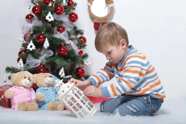 Bambino che gioca vicino all'albero di Natale su uno sfondo bianco — Foto Stock