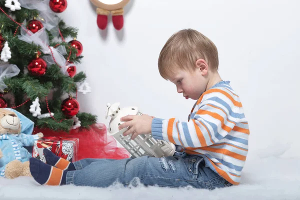 Niño jugando cerca del árbol de Navidad sobre un fondo blanco — Foto de Stock