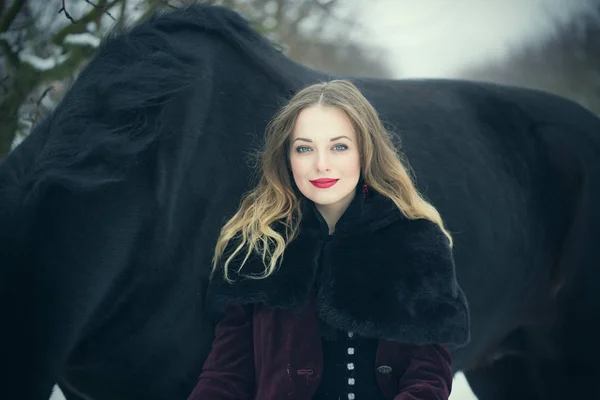 Girl in dark clothes with a black horse — Stock Photo, Image